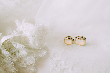 Two wedding gold rings on beautiful white tulle with lace garter close