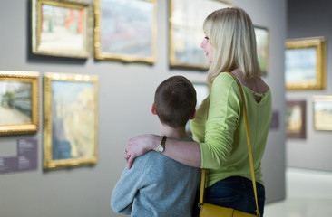 Mother and son looking at paintings in halls of museum