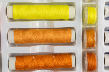 spools and bobbins of sewing threads in orange and yellow