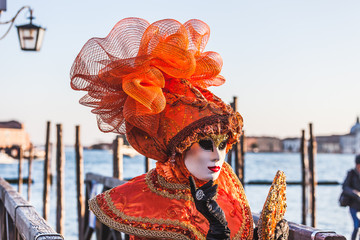 VENICE, ITALY - FEBRUARY 10 2018: Close up of orange dressed carnival mask adorned with fantasy...