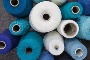 cones of wool and cotton yarn in white, turquois, blue and green