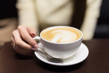 A girl is drinking coffee in a cafe. Small depth of field