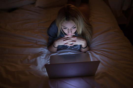A sexy woman lying on bed with laptop at home