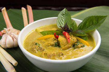 Green Curry With Chicken in bowl with galangal and lemon grass on banana leaf