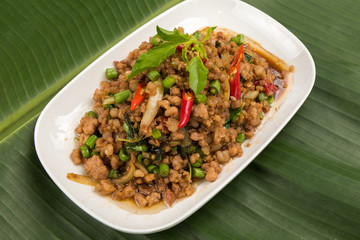 stir fried pork with basil  in white dish on banana leaf