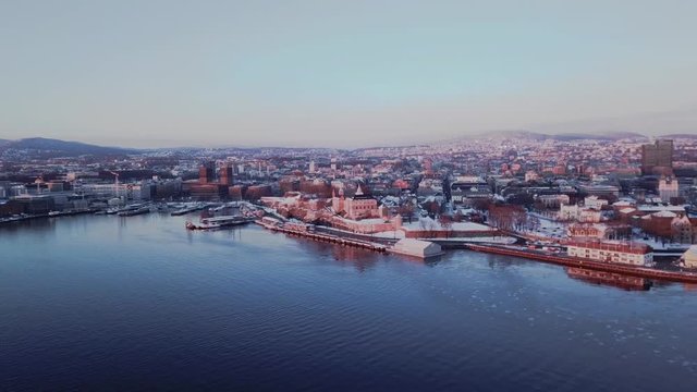Aerial sliding shot towards City Hall and Akershus area in Oslo, Norway at sunset