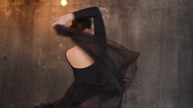 Dancing brunette woman in dancewear and clear dress showing smooth moves. She is spinning pulling her dress up.