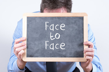 Geschäftsmann mit einer Tafel und dem Motto Face to Face