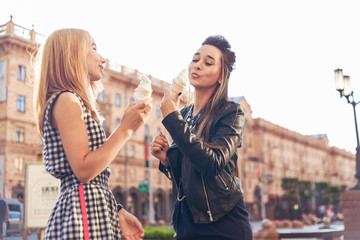 Two best friends having ice cream together outdoors. Young women eating ice cream and laughing.