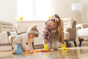 Daughter and mother cleaning home together and having fun.