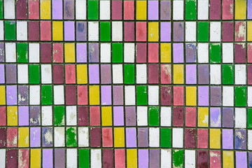 texture of old wall tiles with peeling bright paint.