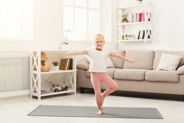 Cute little girl doing yoga exercises at home