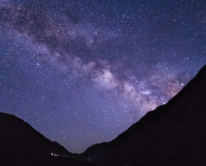 Astrophotography of Milky way. Dark night and bright galaxy above Caucasus mountains in Georgia, Tusheti region. High mountain peak partially covered with snow.
