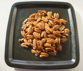 A bunch of nuts pecan on a black plate. Close-up photo 
