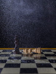 Chess figures on a dark background in the rain. Lose and win Concept. Selective focus