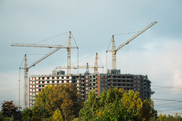 Fototapeta premium future multi-store housing complex with autumn golden yellow grass in sunset sky.