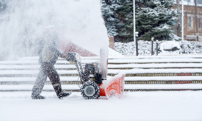Snow-removal work with a snow blower. Man Removing Snow. heavy precipitation and snow pile