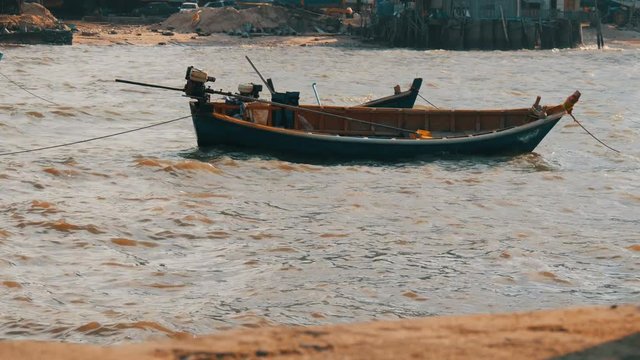 Small fishing boats sail along the lush sea on waves. Fishermen catch fish in the sea