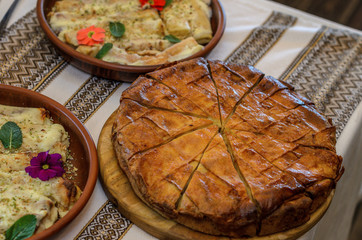 on a tablecloth with a national pattern there is a round cut appetizing cake with stuffing made from pancakes