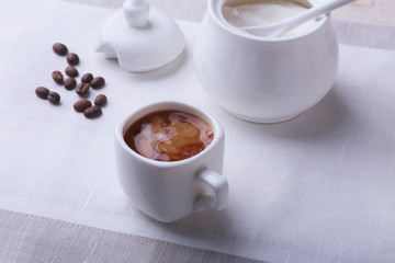 Cup of hot coffee espresso, coffee beans, jug of milk, and bowl with sugar on white background for copy space. Coffee concept.