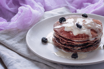 Homemade pancakes or russian blini with coconut cream, maple syrup and dried blueberries. Vegan dessert