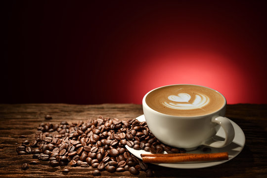 Cup of coffee latte and coffee beans on reddish brown background