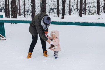 Tattoo and daughter walking with snow-covered pine forest