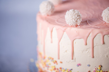 close up detail of white and pink birthday cake with coconut balls selective focus 