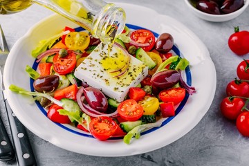 Delicious Greek salad with feta cheese, olives, tomatoes, cucumbers, paprika and red onions.