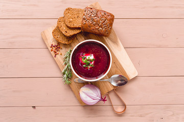 bowl of borscht with pieces of bread and onions on a wooden table