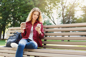 Obraz premium Beautiful woman sitting and using smartphone outdoors