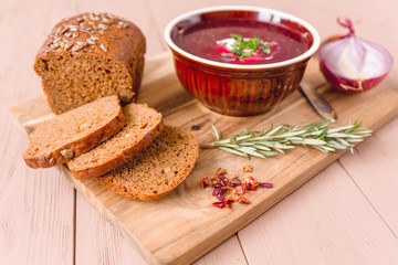 bowl of borscht with pieces of bread and onions on a wooden table