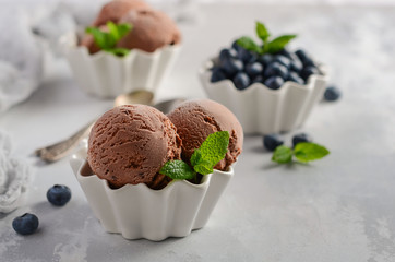 Chocolate ice cream with blueberries on a gray concrete background, selective focus.