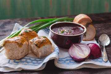 borscht with bread and onions on a wooden table