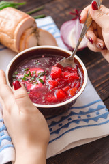 hand of a girl stirs a spoonful of borscht in a plate