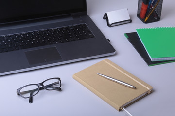 Close-up of comfortable working place in office with laptop, notebook, glasses, pen and other equipment laying on table with copy space.