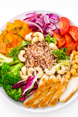 Buddha bowl dish with chicken fillet, brown rice, pepper, tomato, broccoli, onion, chickpea, fresh lettuce salad, cashew and walnuts. Healthy balanced eating. Top view. White background