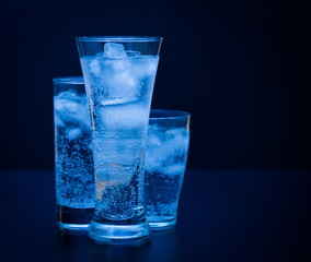 Drink. Water glass and ice, dark background