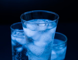 Drink. Water glass and ice, dark background
