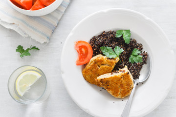 Plate with black quinoa and oatmeal cutlets with prunes on white wooden table with tomato salad and water with lemon. Top View Healthy Vegetarian Food. Copy space