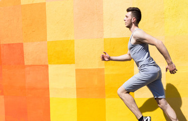 Side view of man running against bright wall