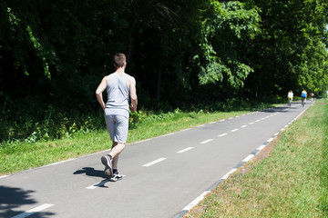 Young man jogging on treadmill in park, copy space