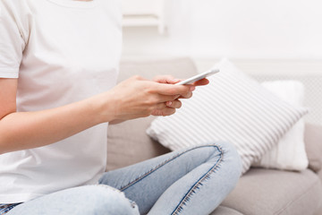 Unrecognizable girl with smarphone sitting on the sofa