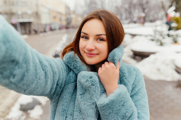 Selfie photo of smiling attractive girl with paper bags after shopping. Laughing pretty woman...
