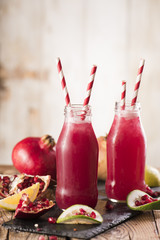 Pomegranate juice with pomegranate on a wooden board on a dark background