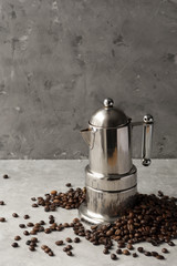 Metal italian moka pot with coffee beans. Espresso maker on grey background.