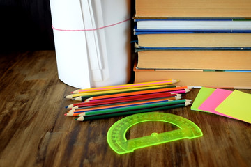 Set of coloured pencils, stickers, books and protractor on a wooden table