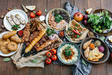Outdoors Food Concept. Appetizing barbecued steak, sausages and grilled vegetables on a wooden...