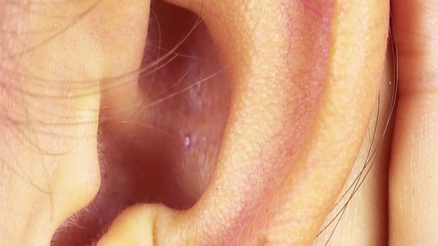 A woman cups her hand around her ear to hear better - closeup