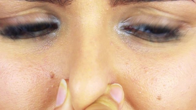 A woman squeezes her nose - closeup